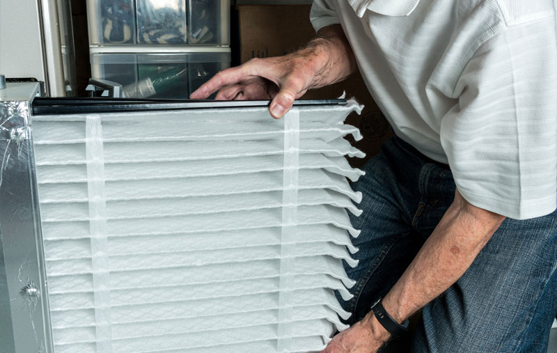 changing-air-filter Technician changing a clean air filter in a furnace